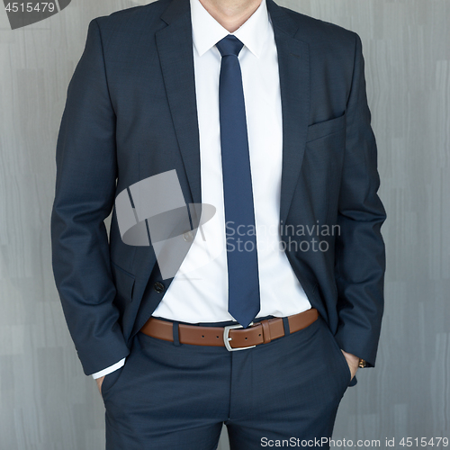 Image of Torso of a businessman standing with hands clenched in middle position in a classic navy blue suit.