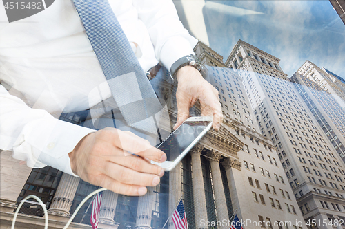 Image of Close up of businessman using mobile smart phone in taxi against New York stock exchange reflection.