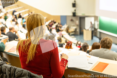 Image of Female student attending faculty lecture workshop making notes.