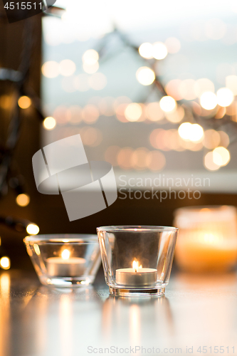 Image of candles burning on window sill with garland lights