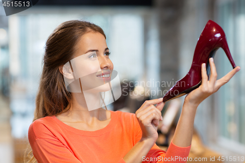 Image of happy young woman choosing shoes at store