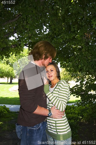 Image of Young couple hugging under the trees in a park