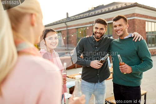 Image of happy friends with drinks hugging at rooftop party