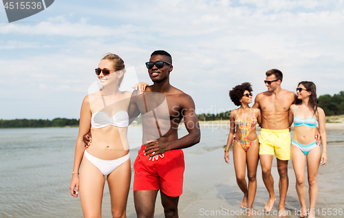 Image of mixed race couple walking along beach with friends