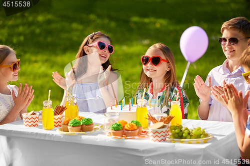Image of happy kids with cake on birthday party in summer