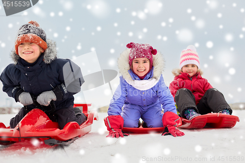 Image of happy little kids sliding down on sleds in winter