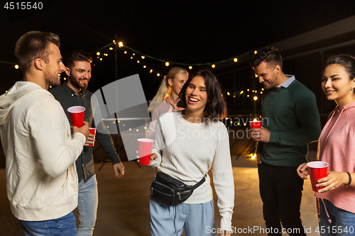 Image of friends with drinks dancing at rooftop party