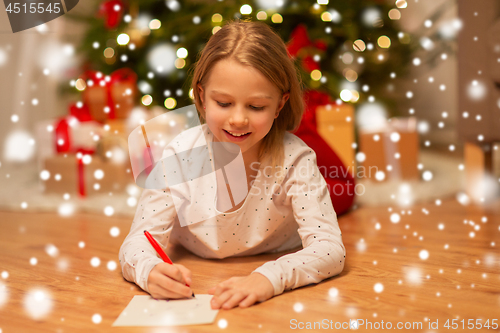 Image of smiling girl writing christmas wish list at home