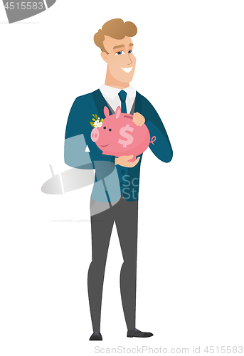 Image of Caucasian groom holding a piggy bank.