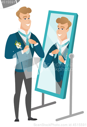 Image of Groom looking in the mirror and adjusting tie.