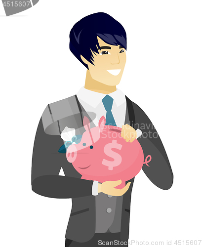 Image of Young asian groom holding a piggy bank.