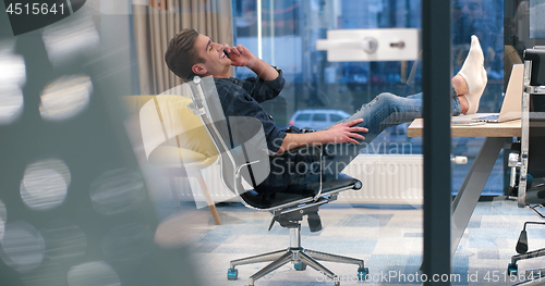 Image of businessman sitting with legs on desk