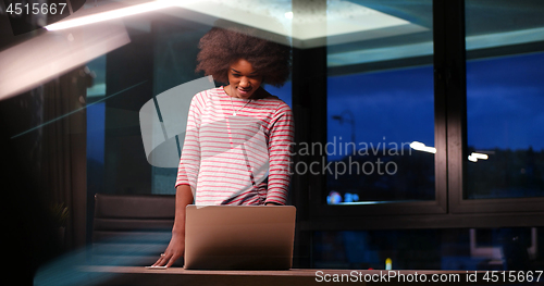 Image of black businesswoman using a laptop in night startup office