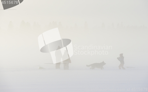 Image of family with a dog in winter on a frozen lake in the fog