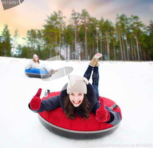 Image of happy teenage girl sliding down hill on snow tube