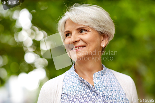 Image of portrait of happy senior woman at summer park