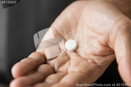 Image of close up of senior man hand with pill