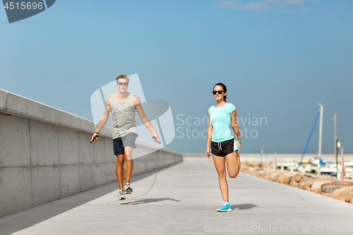 Image of happy couple warming up on pier before training