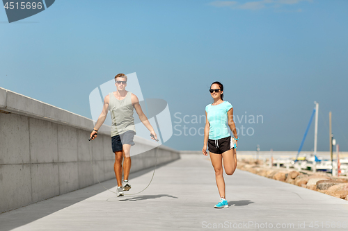 Image of happy couple warming up on pier before training