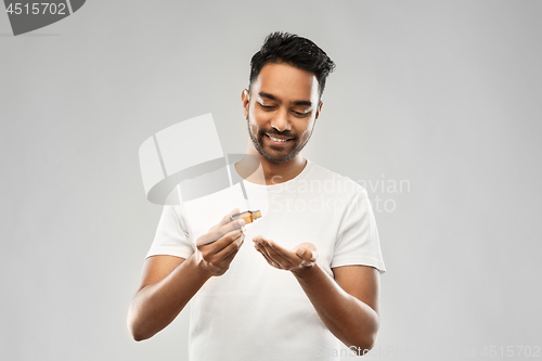 Image of indian man applying grooming oil to his hand