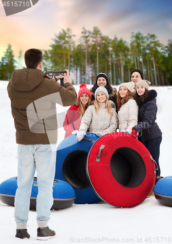 Image of friends with snow tubes taking photo by tablet pc