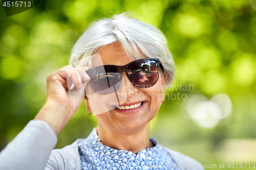 Image of portrait of happy senior woman at summer park