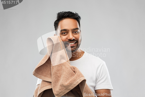 Image of smiling indian man with towel over grey background