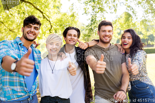 Image of happy smiling friends showing thumbs up at park