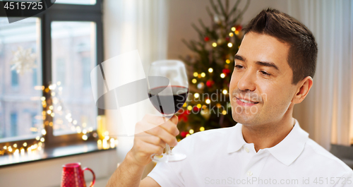 Image of happy man drinking red wine at home on christmas