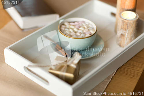 Image of hot chocolate, christmas gift and candles on table