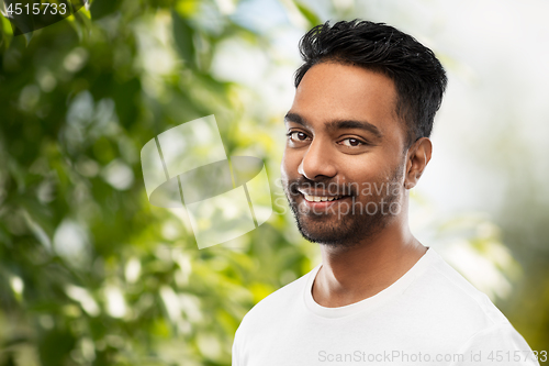 Image of smiling indian man over green natural background