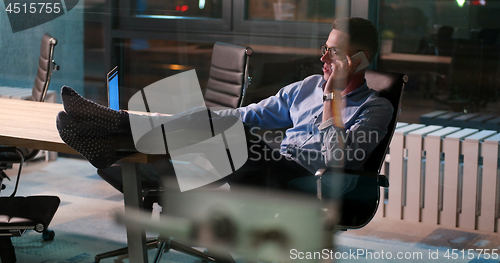Image of businessman sitting with legs on desk at office