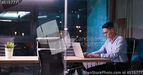 Image of man working on laptop in dark office