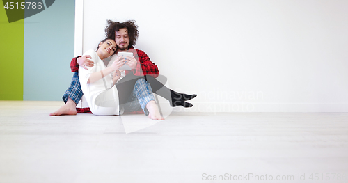 Image of Young Couple using digital tablet on the floor