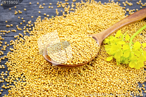 Image of Mustard seeds in spoon with flower on board