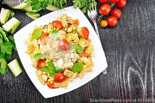 Image of Fusilli with chicken and tomatoes in plate on black board top