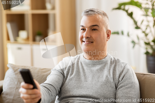 Image of man with remote control watching tv at home