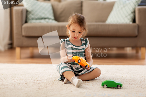 Image of happy baby girl playing with toy car at home