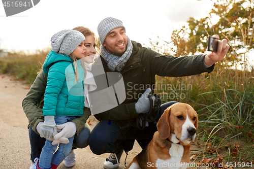 Image of happy family with dog taking selfie in autumn