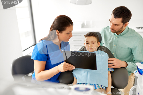 Image of dentist showing tablet pc to kid at dental clinic