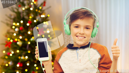 Image of boy with smartphone and headphones on christmas