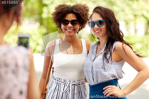 Image of woman photographing her friends in summer park