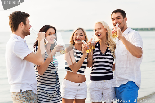 Image of happy friends drinking non alcoholic beer on beach