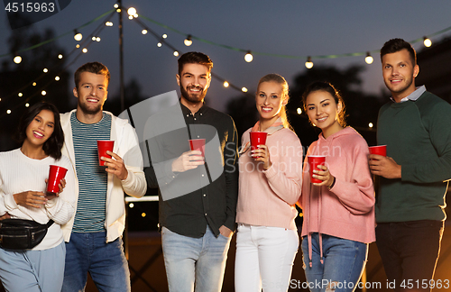 Image of friends with party cups on rooftop at night