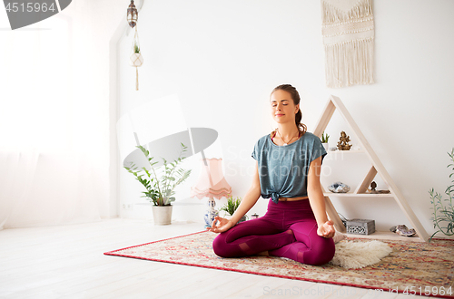 Image of woman meditating in lotus pose at yoga studio