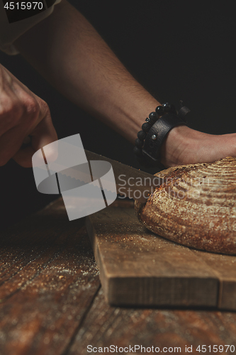 Image of Man slicing tasty fresh bread.