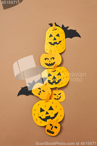 Image of Different handcraft scary pumpkins and bats on a brown background with space for text. Creative composition for Halloween. Flat lay