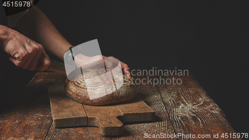 Image of Men\'s hands cut bread