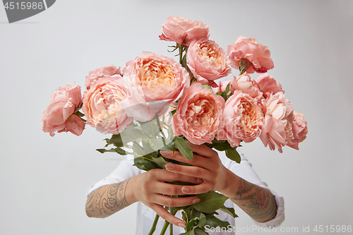 Image of bouquet of fresh pink roses, holding a girl