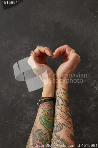 Image of Female hands with tattoos in shape of heart